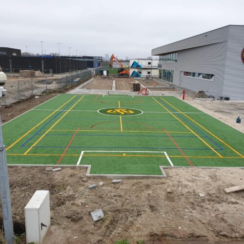 Kunstgras speelvloeren 86 De kunstgras speelvloer van de voetbalkooi is gereed. Met logo, voetbal-, tennis en volleybal-belijningen.